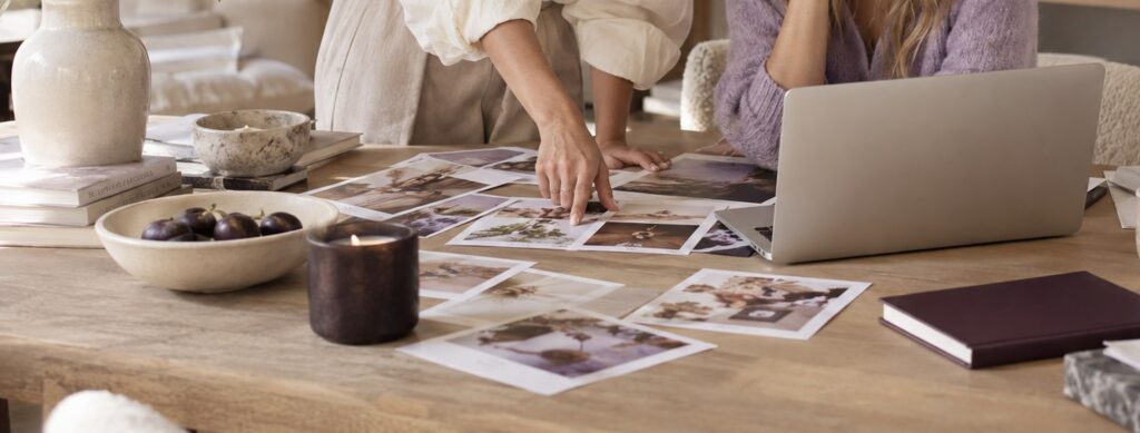 Printed campaign photographs spread across a wooden table during a content review